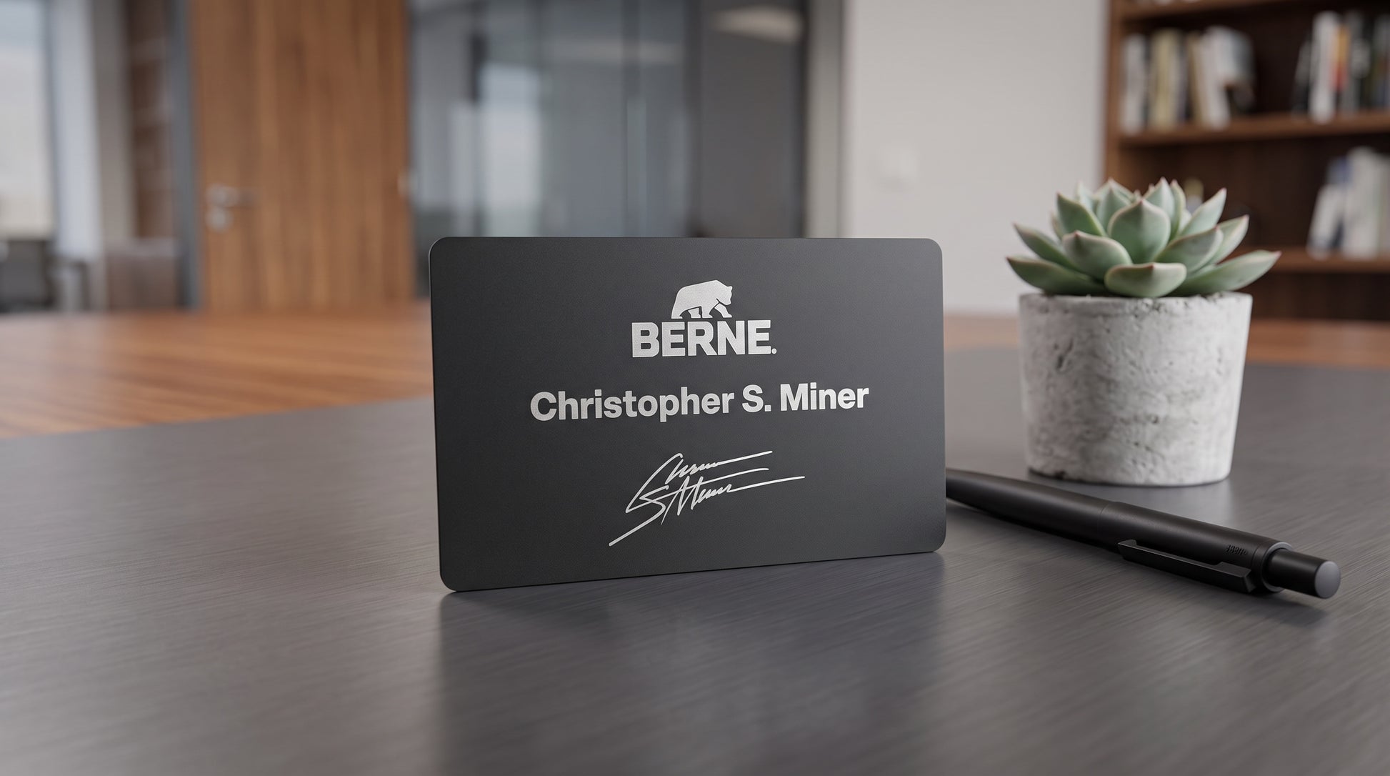 Black matte metal NFC business card standing on a desk